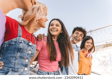 Group of smiling friends, multiracial teenagers wearing colorful casual clothes embracing, walking on the street. Happy stylish boys and girls outdoors. Friendship, positive lifestyle, diversity Royalty-Free Stock Photo #2342090411