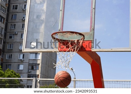 Basketball ball in flight into a basket on a street sports ground