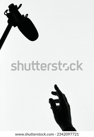 Silhouette of human hand reaching up to a microphone
