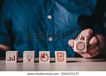 Investment for ultimate goals, Targeting the stock and trade, business development concept. Hand choosing target board which printing on wooden cube block stacking with business strategy plan.