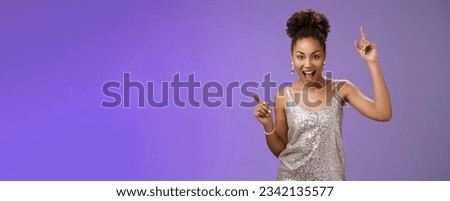 Sassy good-looking african-american woman in trendy glamour silver shiny dress index fingers raised up smiling cheeky joyfully celebrating great lucky news dancing grinning, standing blue background. Royalty-Free Stock Photo #2342135577