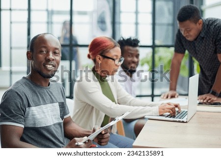 team of employees in a modern office at work. young african american man looking at camera