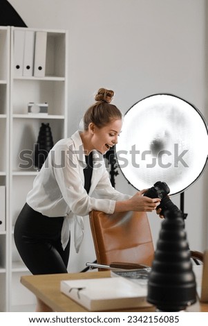 Happy female photographer with professional camera in studio