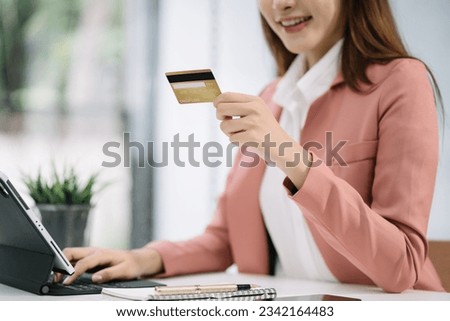 Women use credit cards to pay through tablet and laptop in office.