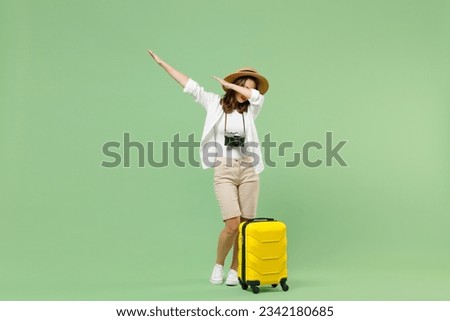 Full length traveler tourist woman in casual clothes hat hold suitcase doing dab hip hop dance gesture isolated on pastel green background. Passenger travel abroad weekends. Air flight journey concept Royalty-Free Stock Photo #2342180685