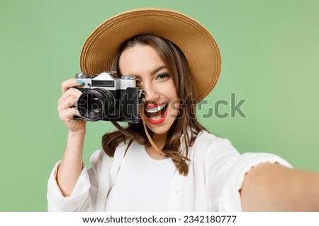 Traveler tourist woman in casual clothes hat taking selfie picture on retro photo camera cell phone isolated on green background Passenger travel abroad on weekends getaway. Air flight journey concept Royalty-Free Stock Photo #2342180777