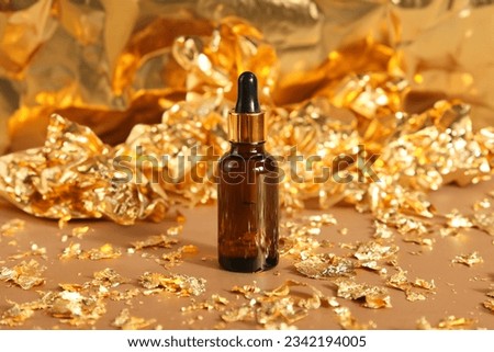cosmetic amber glass essential oil brown bottle, serum in glass bottle with pipette on crumpled golden paper. new year party. mockup, template, front view. cosmetology product for facial care