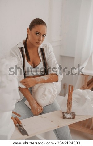 Captivating image of a skilled sculptor, wearing a white shirt and jeans with suspenders, in a relaxed pose with an ancient Greek bust