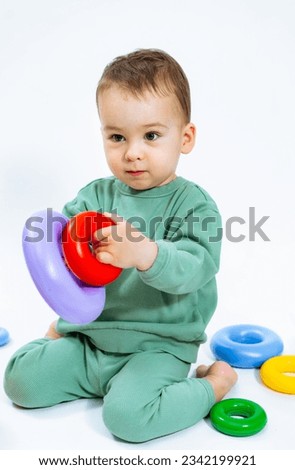Happy baby playing with a colorful toy on the floor. A baby sitting on the floor playing with a toy Royalty-Free Stock Photo #2342199921