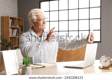 Senior man with tablet computer video chatting at home