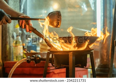 fried noodles cook in pan with big fire flame is hong kong style. Pad Thai favorite and famous Asian Thai street fast food in hot pan, Pad Thai is fried rice noodle dish a street food Thailand Royalty-Free Stock Photo #2342211731