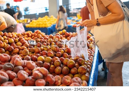 Female housekeeper buy ripe nectarines at farmer market Royalty-Free Stock Photo #2342215407