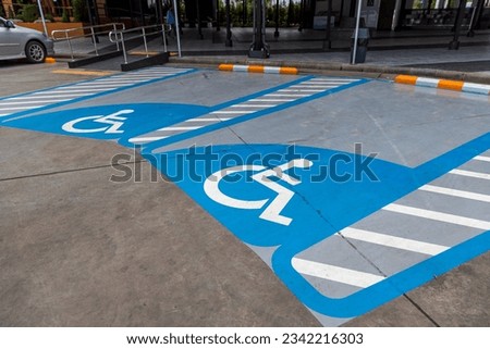 Parking for disabled or wheelchair. A sign indicates reserved parking for disabled people in a car park.  International handicapped symbol painted in bright blue on a shopping center parking space. 