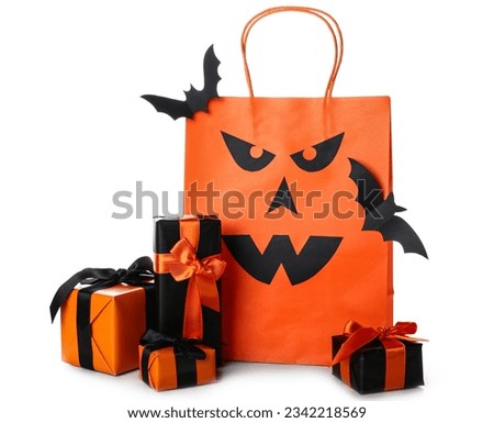 Orange shopping bag, gift boxes and paper bats for Halloween on white background
