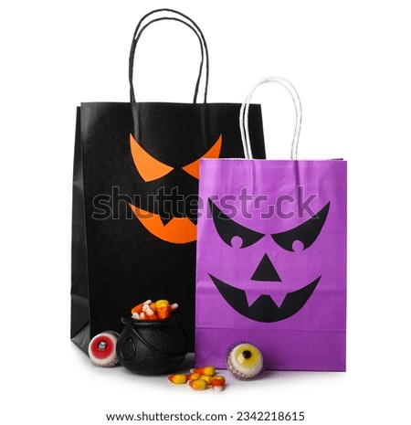 Different shopping bags and tasty candies for Halloween on white background