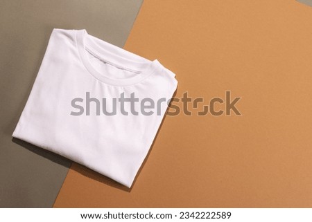 Close up of folded white t shirts and copy space on brown background. Fashion, clothes, colour and fabric concept.