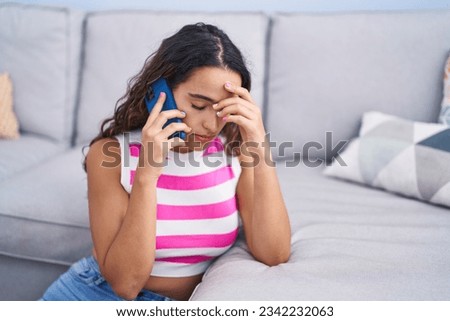 Young beautiful hispanic woman talking on smartphone with worried expression at home Royalty-Free Stock Photo #2342232063