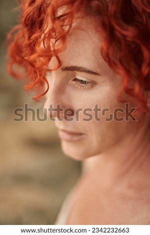 Portrait middle age woman with red curly hair looking at sea. Summer holiday rest, grounding slowing harmony time for business woman