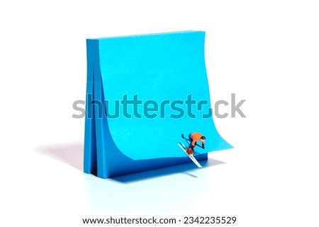 Creative miniature people toy figure photography. Winter sport sticky notes installation. A male downhill ski racer slides down from the top of the hill. Image photo