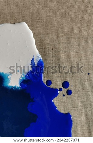 Navy blue and white paint spilled on linen canvas, blot
