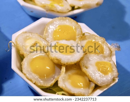 a photography of a bowl of fried eggs with a side of salad, there are some fried eggs in a bowl on a table.
