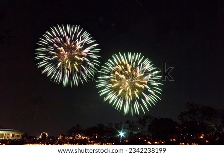 a photography of a couple of fireworks that are in the sky, fireworks are lit up in the night sky above a lake.