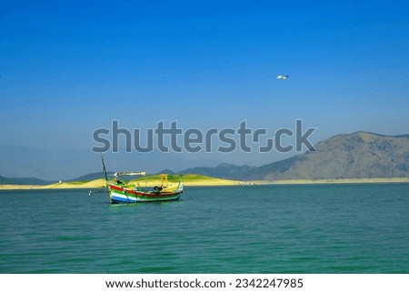 amazing view of Tarbela lake with wooden boats on the water, surrounded by mountains.
