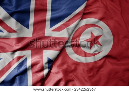 big waving national colorful flag of great britain and national flag of tunisia . macro Royalty-Free Stock Photo #2342262367