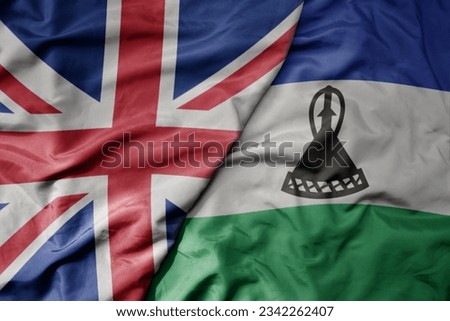big waving national colorful flag of great britain and national flag of lesotho . macro