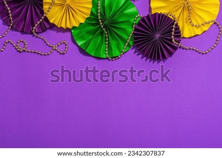 Festive Mardi Gras masquerade purple background. Fat Tuesday carnival, beads, traditional decor. Symbolic colors, trendy hard light, dark shadow, flat lay, top view Royalty-Free Stock Photo #2342307837