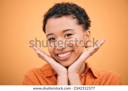 Happy, woman and hands on face in studio with smile and confidence feeling cute. Orange background, young portrait and African female person with trendy, modern and student fashion of gen z glow