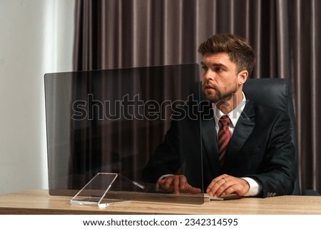 A futuristic businessman looks at an empty transparent monitor screen, ready to add graphics or pictures. This image is perfect for use in presentations, marketing materials, or website designs.