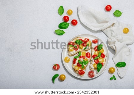 Fresh bread sandwiches with tomato cherry, cream cheese and basil leaves. Morning breakfast concept. Hard light, dark shadow, white stone concrete background, top view Royalty-Free Stock Photo #2342332301