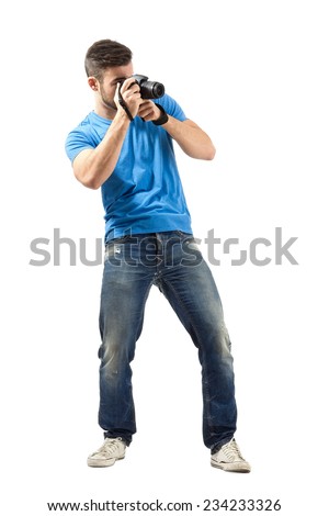 Standing young man taking photo with dslr. Full body length portrait isolated over white background.