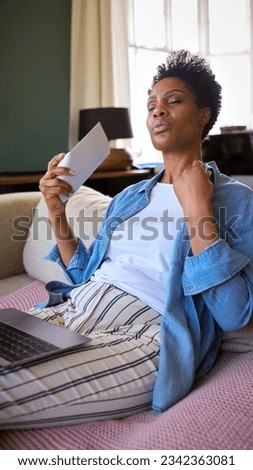 Menopausal Mature Woman At Home With Laptop Having Hot Flush Fanning Herself Royalty-Free Stock Photo #2342363081