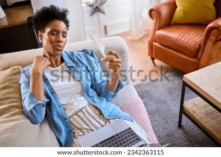 Menopausal Mature Woman At Home With Laptop Having Hot Flush Fanning Herself Royalty-Free Stock Photo #2342363115