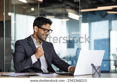 Young successful arab businessman at workplace inside office, man in business suit with laptop celebrating victory received online win notification, boss winner rejoices and celebrates triumph. Royalty-Free Stock Photo #2342368215