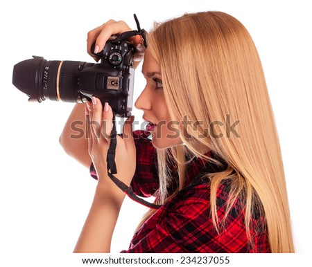 Attractive female photographer holding a professional camera and making pictures  - isolated on white