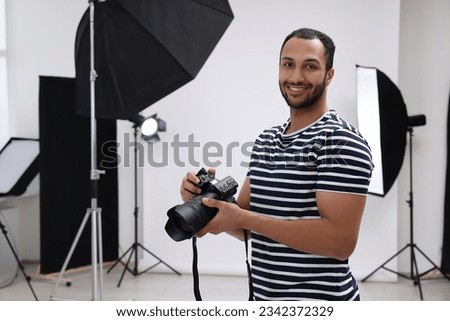 Professional photographer with camera in modern photo studio, space for text