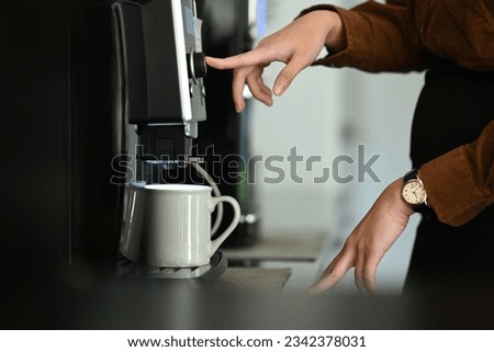 Closeup business woman using coffee machine in the office. Royalty-Free Stock Photo #2342378031