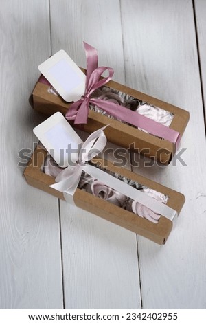 Homemade marshmallows in paper gift boxes. Zephyr flowers. The boxes are tied with a ribbon tied into a bow.