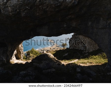 Views of the sea and the coast of Sonabia and Oriñon from the Ojos del Diablo cave, on Mount Candina. With a young woman in the middle hiking