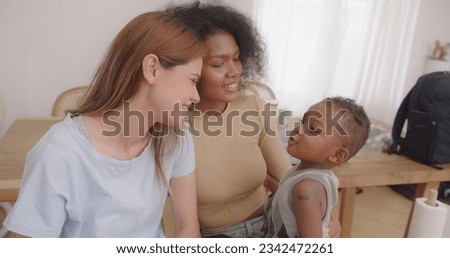 Smiling Lesbian Couple Sharing a Tender Kiss while Embracing their Son - A Celebration of Love and Family in the Living Room