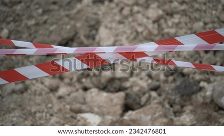 Red white barrier tape trenches. Focus on red and white barrier tape at construction site. Ribbons indicate dug trenches.