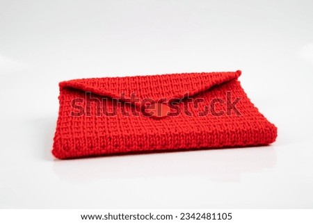 Red knitted purse, a creative handmade accessory in soft wool. This stylish and trendy needlework can make women happy.