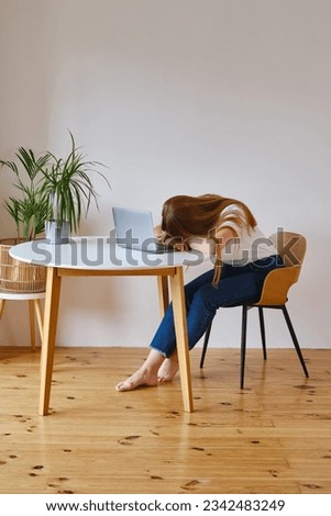 A young girl fell asleep in front of a laptop. Pretty woman is tired or overworked. Cozy home environment Royalty-Free Stock Photo #2342483249