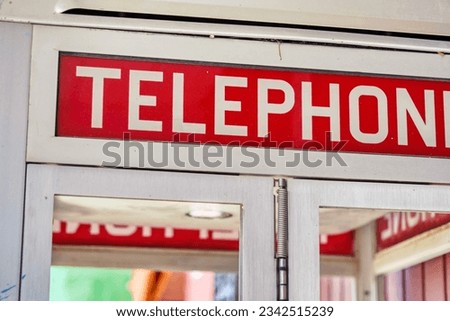 A closeup of a red sign on a telephone booth outdoors