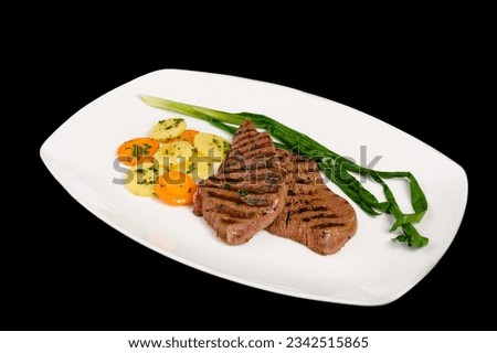 Steaks. A pieces of steak with grilled vegetables. Isolated on black