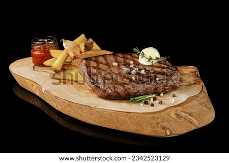 Steak seared on the barbecue  on top with herb butter with french fries on cutting board