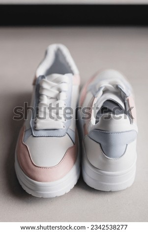 Close up details of pink, blue and white leather sneakers with white sole and white laces on the floor. Casual fashion style minimalistic shoes.